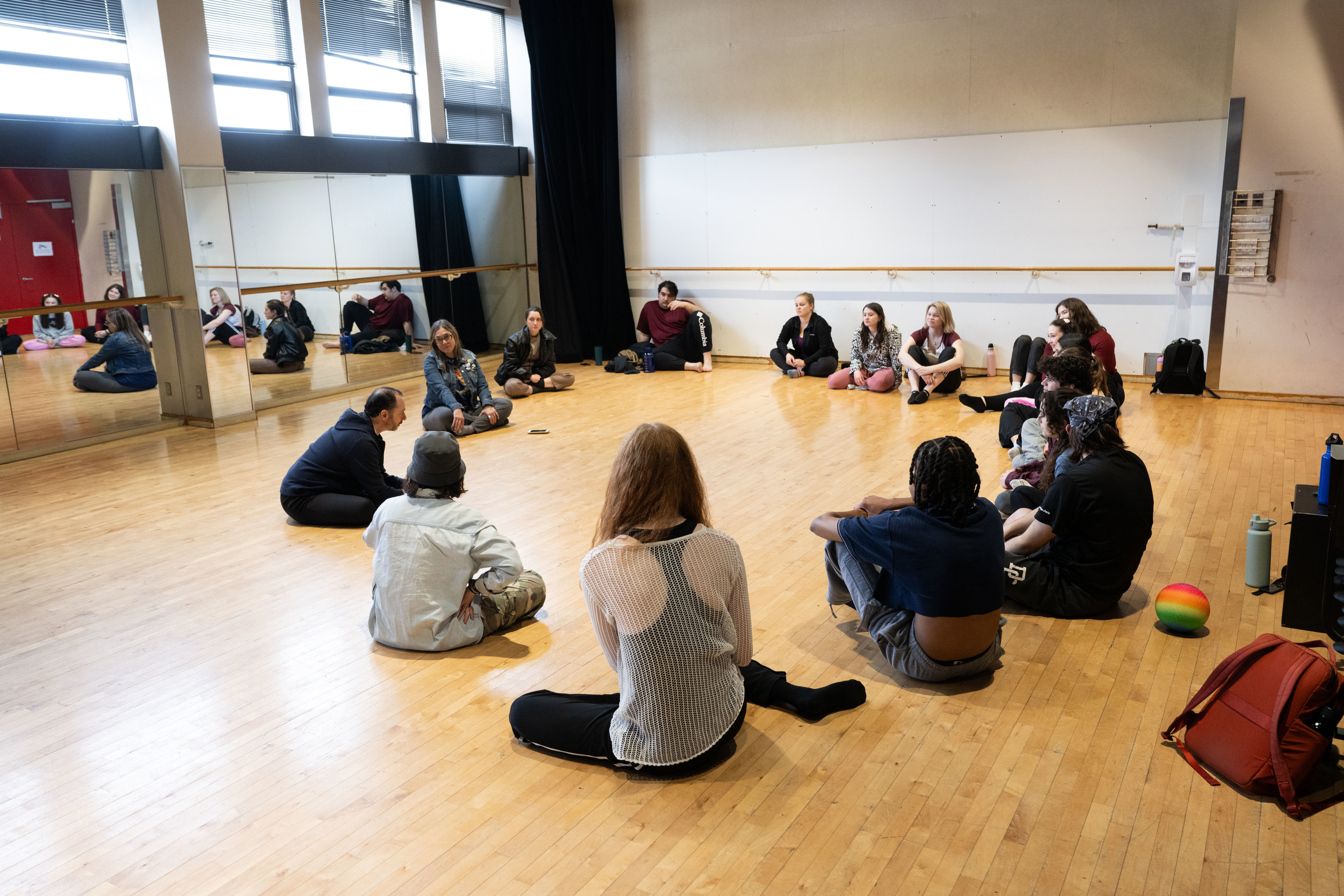 UI Theatre Arts students sit in a circle with a guest artist from Les Ballets Trockadero de Monte Carlo