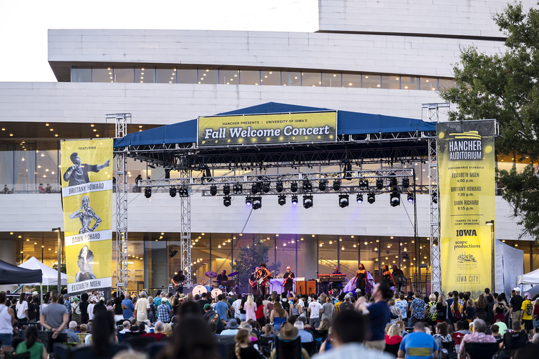 A crowd stands in front of an outdoor stage set up outside Hancher Auditorium. Brittany Howard performs.